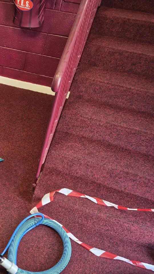 The staircase carpet at Ochilview Park, with a hose and hazard tape laid out during a clean.