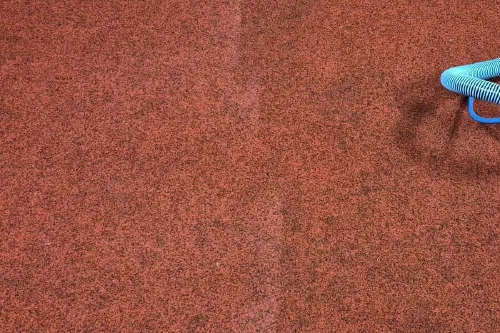 A large area of carpet part way through cleaning, with a soft vertical line across it: the carpet to the left has been cleaned and is still damp, the carpet to the right has not.